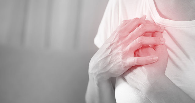 Female holding her chest highlighting that they might be having a cardiac event.